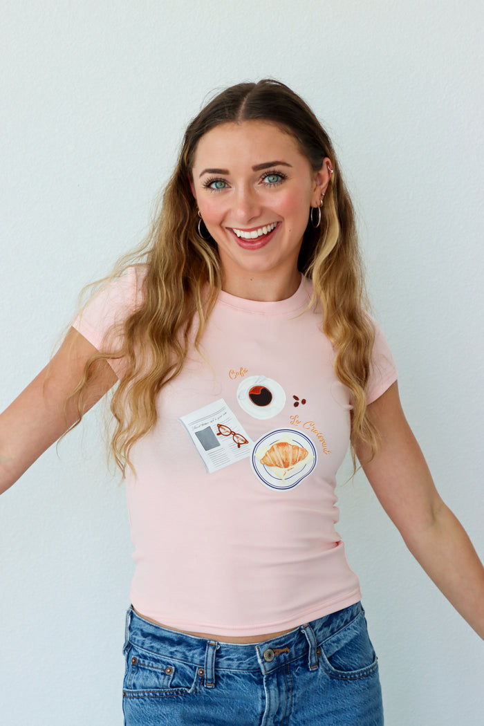 Woman wearing a pink t-shirt with graphic designs on a plain background