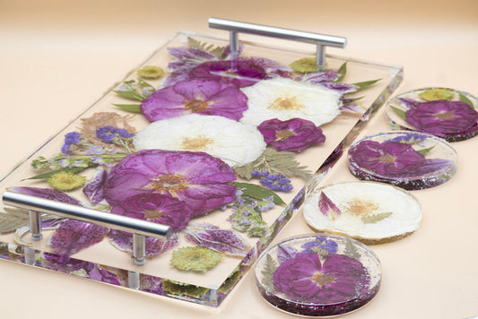 Landscape photo of a pressed flower round resin tray with mixed dried botanical layers on a dark surface