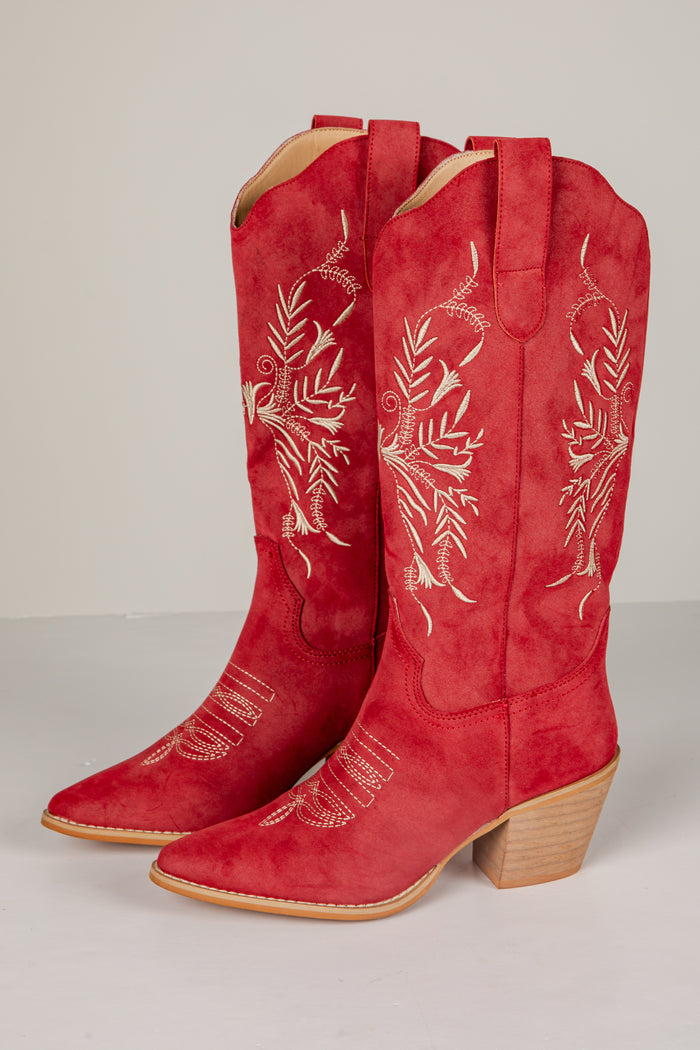 Red cowboy boots with white embroidery on a light gray background