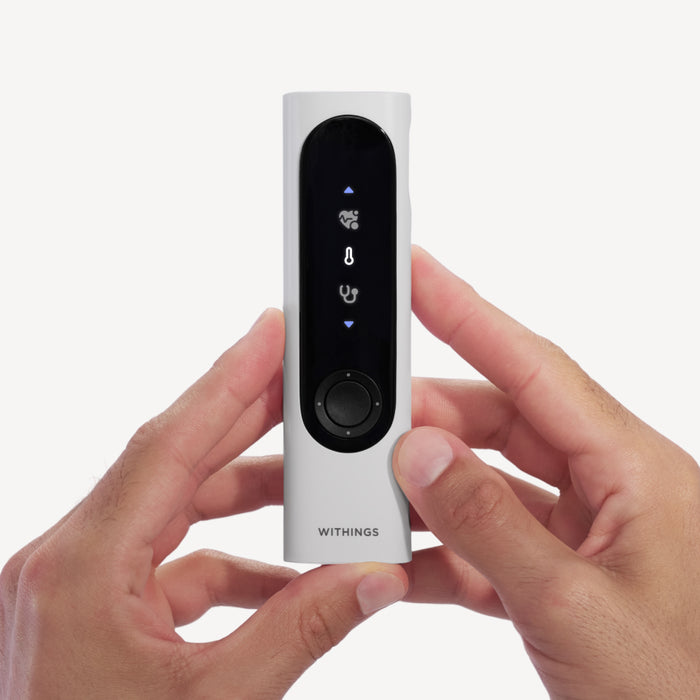 Withings BeamO — Beam-O — Front view held in two hands, black display with medical icons and rotary button, white casing on plain background — handheld, front-facing, close-up, white