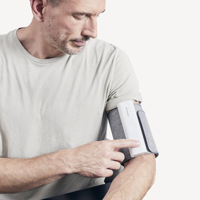 Withings BPM Connect — Connected — Man pressing button on cuff worn on left upper arm, clean white background — cuff, blood pressure, arm, close-up