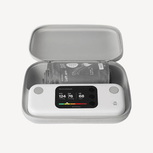 BPM Vision — Connected Blood Pressure Monitor — Top-down view in open grey travel case, screen showing SYS 124 DIA 76 HR 68, cuff folded inside — travel case, lit display, top-down, open case