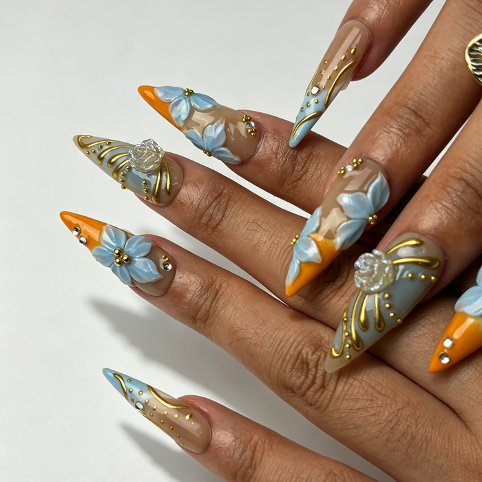 Close‑up summer press‑on nails, 3D pale blue flower gold swirl rhinestone manicure