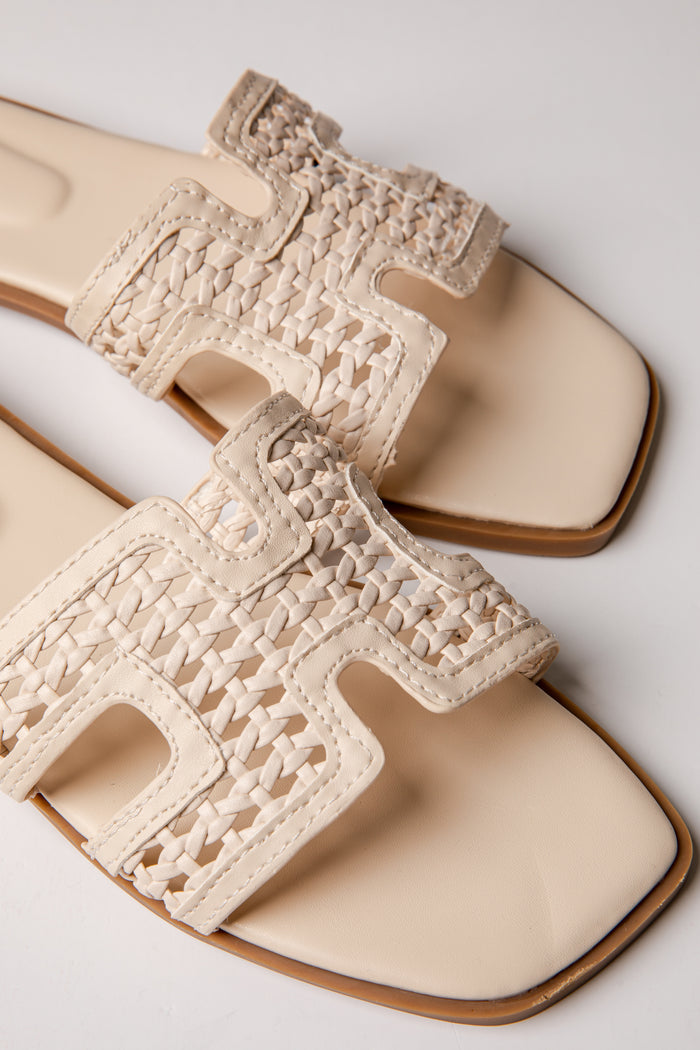 Beige sandals with crochet detailing on a light gray background