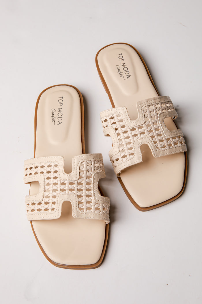 Pair of beige sandals with decorative 'H' design on a light gray background