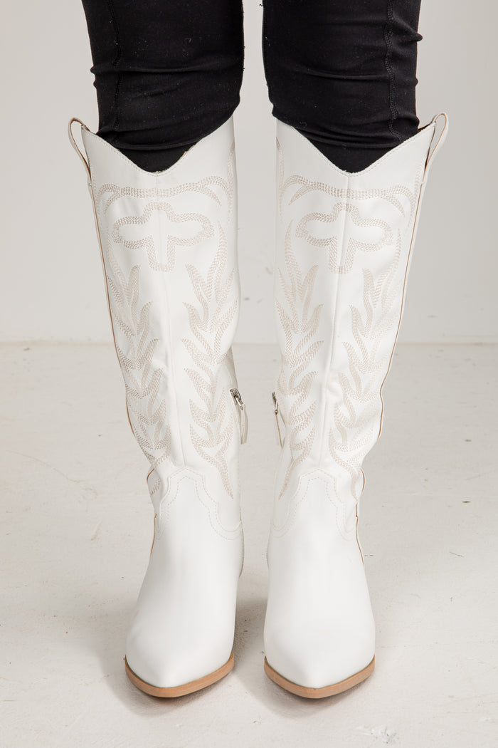 White embroidered knee-high boots on a white background
