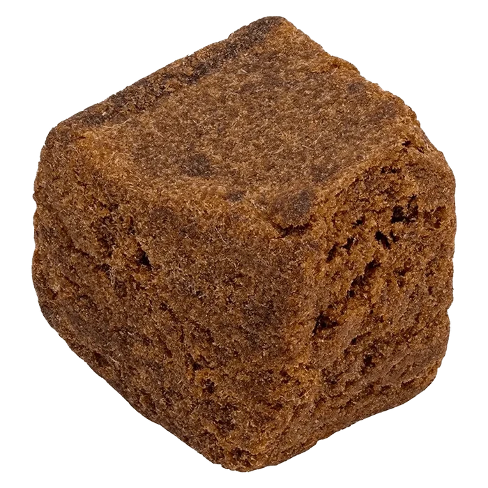Close-up three-quarter view of the brown Hash cube, showing its dense, crumbly texture and rough, uneven surfaces.