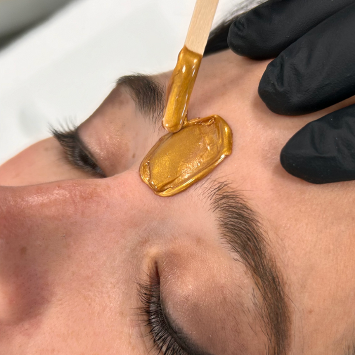 W500 Italwax 500g Candy Cane Film Wax | Person receiving a facial wax treatment with a gold Gingerbread Italwax film wax on their face.