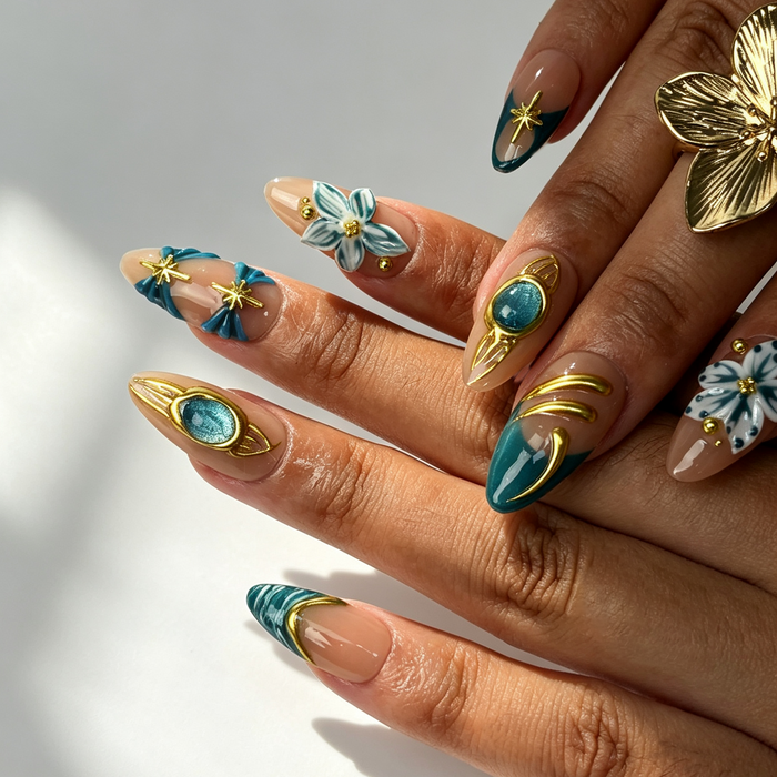 Close‑up handmade press‑on nails, gold gem frame dual‑tone blue flower manicure