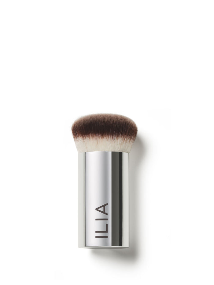 A close-up of the Perfecting Buff brush with a silver handle and densely packed, dual-toned bristles.