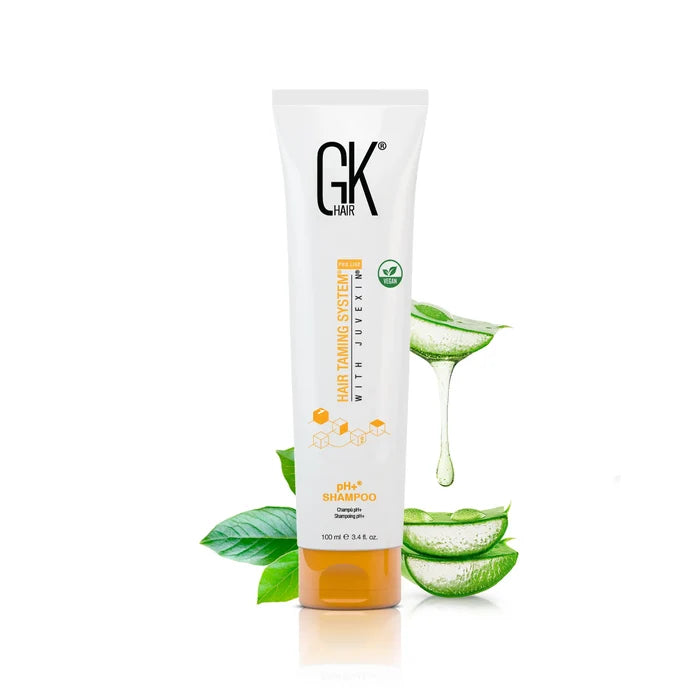 GK Hair pH+ Shampoo 100 ml white tube with an orange cap beside aloe vera leaves and dripping aloe gel