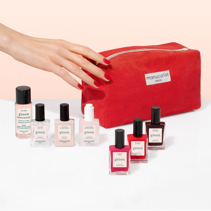 A hand with red nails reaches for the Manucurist Starter Kit pouch, displayed alongside plant-based nail polish and gel effect products.