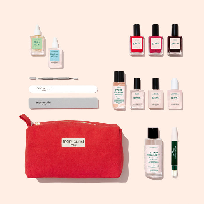 A flat lay of the Manucurist Ultimate Kit features gel effect nail polish, nail care bottles, files, a cuticle tool, a green cuticle pen, and a red pouch—everything needed for the perfect at-home manicure on a beige background.