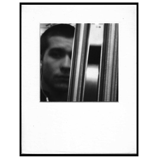 black and white photo of a pole obscuring a man's face