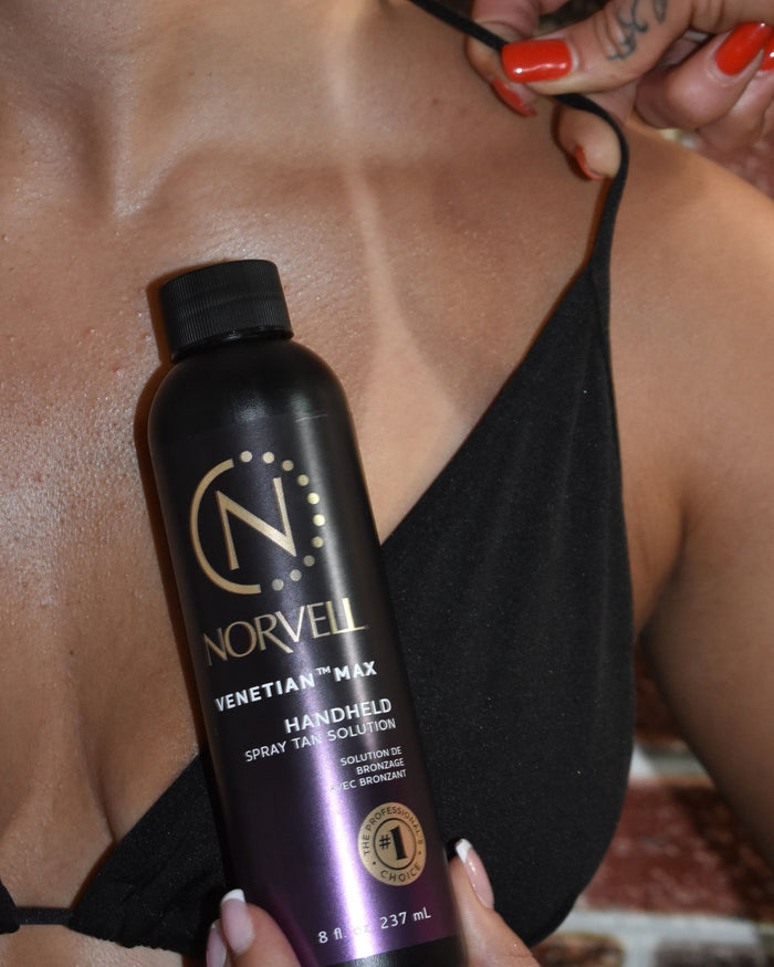 Norvell tanning solution bottle held by a person with a fresh Venetian Max tan wearing black Norvell bikini top revealing a tan line.