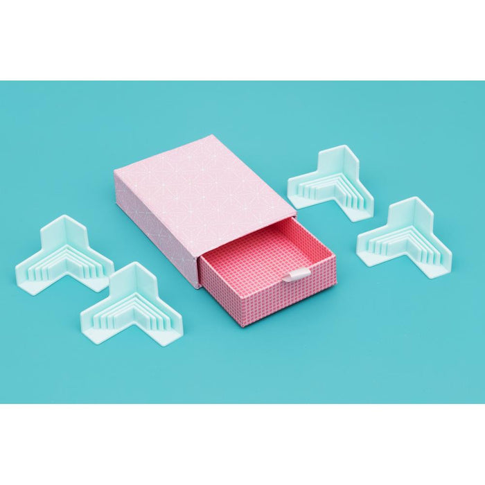 We R Memory - Corner Guides - 4/Pkg. Great for boxes, book covers, dioramas, and more! Holds corners tightly while adhesive sets. Works with 3mm, 2mm, 1.5mm, and 1mm wide chipboard. Imported. Available at Embellish Away located in Bowmanville Ontario Canada.